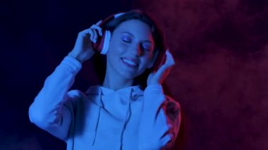 Çekici genç bir kadının portresi büyük kırmızı kulaklıklarla dans edip müzik dinlemektir. Kapatın. Yavaş çekim.