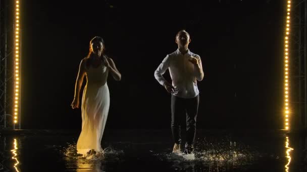 Una pareja bailando salsa en blanco. Baile hermoso caliente apasionado realizado en un estudio oscuro en una superficie de agua con muchas salpicaduras. Movimiento lento. — Vídeos de Stock