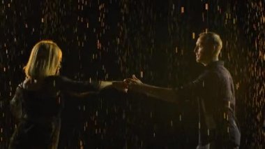 Profesyonel dansçılar karanlık dumanlı bir stüdyoda salsa yapıyorlar. Yağmurda siyah elbiseli dans partnerlerinin siluetleri ağır çekimde hareket ediyor. Kapat..