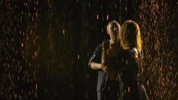 Bailarines profesionales realizan elementos de salsa en un estudio ahumado oscuro. Siluetas de parejas bailando en ropa negra bajo la lluvia, moviéndose en cámara lenta. De cerca.. — Vídeo de stock