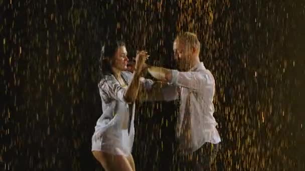 Hombre y mujer mojados de la lluvia, bailan un baile de salsa apasionado y elegante. Las gotas de lluvia brillan sobre un fondo negro en la luz del estudio. En cámara lenta. De cerca.. — Vídeos de Stock