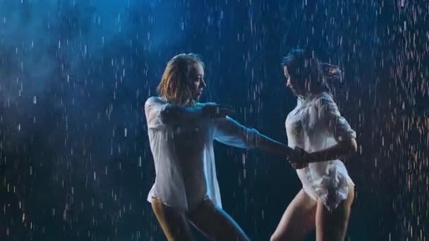 Okouzlující vášnivé blondýny a brunetky tančí a hladí se na pozadí lesklých kapek deště a kouře. Mokré ženy se pohybují eroticky zpomaleně. Zavřít. — Stock video