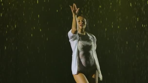 Des danseuses dansent des éléments de salsa sous la pluie battante. Silhouette d'une femme en vêtements mouillés appréciant la danse. Au ralenti. Gros plan. — Video