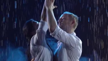 Karanlık bir stüdyoda dans eden tatlı, gülümseyen bir çift. Beyaz elbiseli bir adam ve bir kadın danstan zevk alıyorlar. Ağır çekim. Kapat..