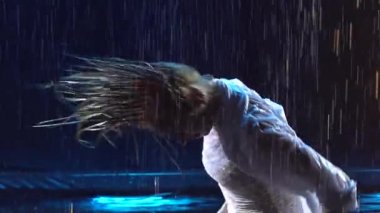 İki seksi güzel kadın, erotik olarak yağmur ve duman damlalarının arasında hareket ediyor. Islak elbiseli dansçılar tutkulu bir şekilde ağır çekimde poz verirler. Kapat..