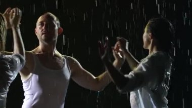 Karanlık dumanlı arka planda salsa dansının tutkulu hareketleri. Yavaş çekimde baştan çıkarıcı hareket eden üç ıslak vücuttan oluşan bir siluet. Kapat..