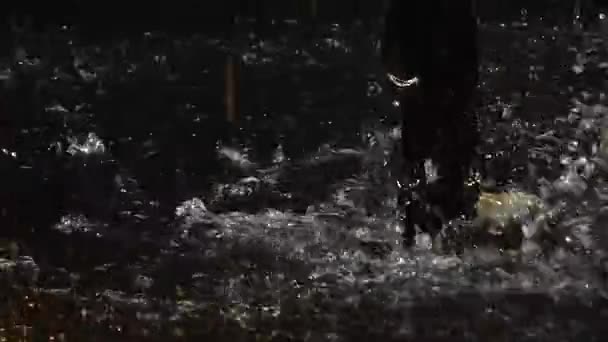 Um dançarino latino esbelto dança elementos de salsa com um parceiro na chuva em um estúdio escuro. Os dançarinos estão molhados da chuva apreciando a dança. Torso e pés descalços fechar em câmera lenta. — Vídeo de Stock