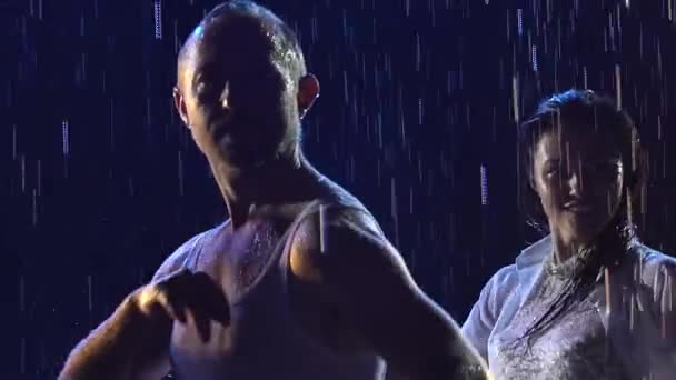 Krásný pár tancující latinský tanec. Profesionální tanečníci tančící salsu mezi lesklými kapkami deště na tmavém pozadí studia. Zavřít ve zpomaleném filmu. — Stock video