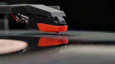 Yan izleme plağı eski okul pikabında dönüyor. Vintage bir turntable 'da müzik albümü çalarken geniş açılı bir çekim. Siyah arka planda geçmişe dönük plak çalar. Yavaş çekim.