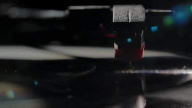 Ön izleme plağı DJ pikabında dönüyor. Bir iğne ve bir ışık demeti tarafından aydınlatılmış siyah bir kayıt. 80 'lerin popüler disko stili. Yavaş çekim.