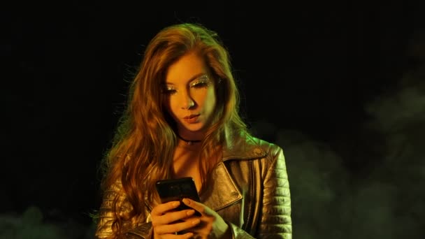 Portret młodej ładnej kobiety radośnie pisze na swoim telefonie, a następnie pokazuje smartfona z niebieskim kluczem do chromy i wskazuje na niego palcem. Zamknij drzwi. Zwolniony ruch. — Wideo stockowe