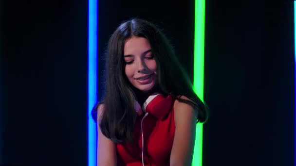 Portret van een jong mooi meisje in grote rode koptelefoon danst en geniet van de muziek. Sluit maar af. Langzame beweging. — Stockvideo