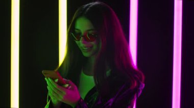 Şık güneş gözlüklü güzel bir kadının portresi akıllı telefonuyla mesaj atıyor. Kapatın. Yavaş çekim.