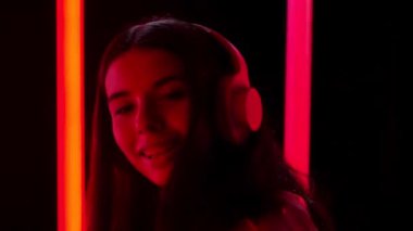 Güzel, genç bir kadının portresi müzik dinliyor, büyük beyaz kulaklıkları var ve dans ediyor. Kapatın. Yavaş çekim.