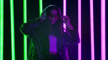 Müzik dinleyen ve büyük beyaz kulaklıklarla dans eden güzel genç bir kadının portresi. Yavaş çekim.