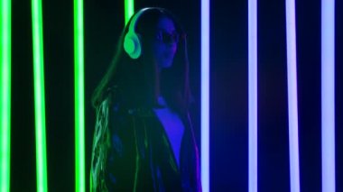 Güzel genç bir kadının portresi. Büyük beyaz kulaklıklarla müzik dinliyor ve sakızdan baloncuklar üflüyor. Yavaş çekim.