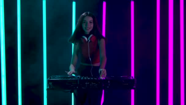 Retrato de una joven mujer bonita con grandes auriculares rojos tocando un set musical mientras bailaba cerca del tocadiscos DJ. Movimiento lento. — Vídeos de Stock