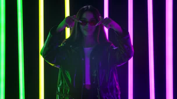 Portrait of a pretty young beautiful woman in stylish sunglasses looking at the camera shows a heart gesture with her hands and sends an air kiss. Slow motion. — Stock Video