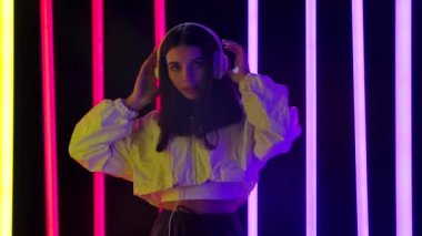 Güzel genç bir kadının portresi büyük beyaz kulaklıklarla müzik dinlemekten hoşlanır. Yavaş çekim.