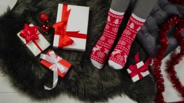 Noel çoraplı, kırmızı ve beyaz süslemeli bir kadın gri kürklü bir tende oturuyor. Hediyeler, mücevherler ve süsler etrafa saçıldı. Tatil randevusu. Mutlu Noeller ve yeni yıl. Kapatın. Yavaş çekim.