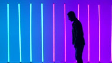 Profesyonel dansçı tarafından icra edilen Breakdance akrobatik elementler parlak renkli neon ışıkların arka planına karşı. Takla atan bir adamın silueti. Kapatın. Yan görüş. Yavaş çekim.