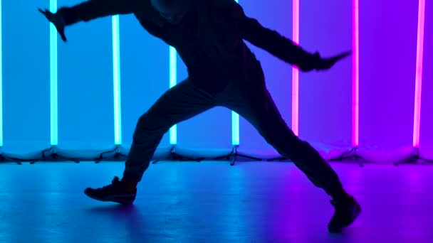 Profesyonel bir dansçı tarafından icra edilen Breakdance akrobatik elementler parlak renkli neon ışıkların arka planına karşıdır. Amuda kalkıp dönen bir adamın silueti. Kapatın. Yavaş çekim — Stok video