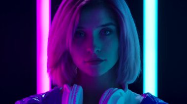 Büyük beyaz kulaklıklı, kameraya bakan genç ve şık bir kadının portresi. Kapatın. Yavaş çekim.