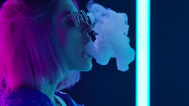 Портрет молодої стильної жінки в сонцезахисних окулярах, яка палить кальян і вириває пуфи диму. Близько. Повільний рух . — стокове відео