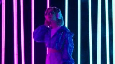 Güneş gözlüklü ve büyük beyaz kulaklıklı genç bir kadının portresi dans ediyor ve yavaş müzikten hoşlanıyor. Yavaş çekim.