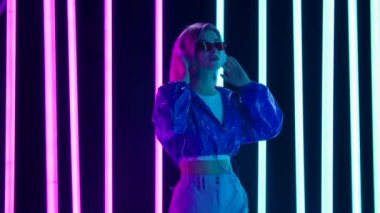 Güneş gözlüklü ve büyük beyaz kulaklıklı genç bir kadının portresi dans ediyor ve yavaş müzikten hoşlanıyor. Yavaş çekim.