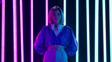 Büyük beyaz kulaklıklı, kameraya bakıp gülümseyen genç bir kadının portresi. Yavaş çekim.