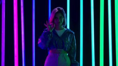 Genç ve şık bir kadının portresi kameraya bakıp gülümsüyor ve iyi bir jest gösteriyor. Yavaş çekim.