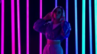 Güneş gözlüklü genç bir kadının portresi büyük beyaz kulaklıklar ve sakızla müzik eşliğinde dans ediyor. Yavaş çekim.