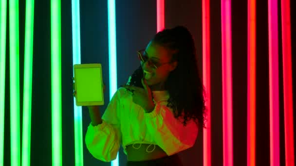 Retrato de una joven encantadora mujer afroamericana señala con el dedo el teléfono inteligente con la tecla croma pantalla verde, haciendo rock y pulgares hacia arriba gesto. Movimiento lento — Vídeos de Stock