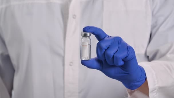 Presentation of vaccine from COVID-19 coronavirus. Doctor holds in his hand a vial bottle with an invented vaccine. Global pandemic finishes. Vaccine dose close up. Slow motion. — Stock Video