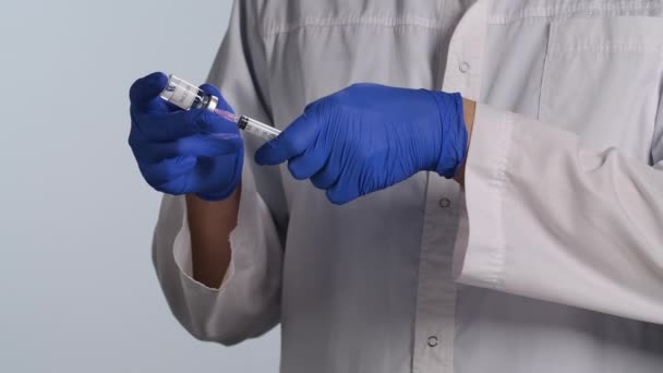 Dokter dan ditembak untuk disuntik. Dokter menyiapkan jarum suntik dengan vaksin. Seorang pekerja medis berpengalaman memegang botol kecil di tangan. Imunisasi terhadap virus COVID, pengobatan flu. Tutup. Gerakan lambat. — Stok Video