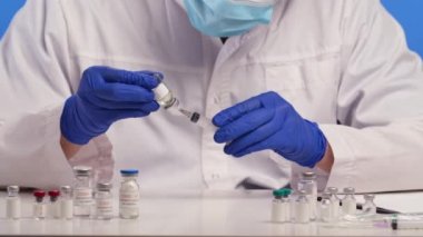 Koruyucu eldivenler giymiş bir tıp çalışanı, aşı örneklerini şırıngaya çekiyor ve günlük yazısı yazıyor. Koronavirüs için aşı, ilaç ve antibiyotik geliştirildi. Kapatın. Yavaş çekim.