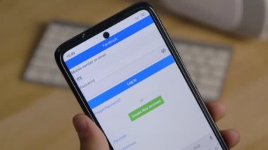 Editör görüntüleri: Akıllı telefon taşıyan beyaz bir adamın elleri ve giriş yapmak veya Facebook sosyal ağına kayıt olmak için dokunmatik ekranda klavye tuşları. Kapatın. Yavaş çekim.