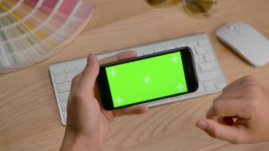 Akıllı telefonu yatay modda kullanan bir adamın elleri. İçeriği yakından izleme ya da izleme düzeni. Sosyal medya ya da online alışveriş sayfalarına bakıyorum. Yeşil ekran, krom anahtar. Yavaş çekim.
