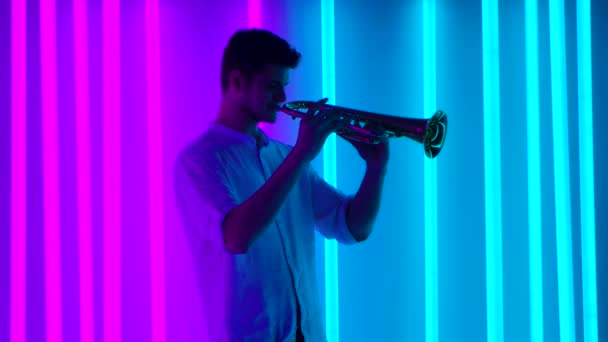 Show of music and lights. A professional trumpet player performs a music concert in a dark studio with bright multicolored neon tubes. Nightlife concept. Slow motion. — Stock Video