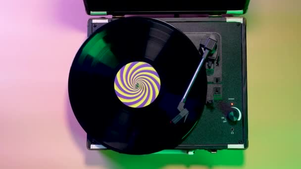 Giradischi retrò musicale con un disco di vinile rotante su uno sfondo di luci al neon luminose. Vista dall'alto momento di avvicinamento ad una lastra in vinile girevole nera. Chiudete. Rallentatore. — Video Stock