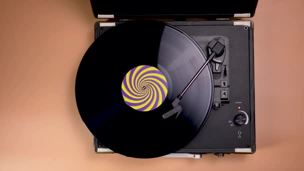 Top view παλιά vintage όμορφη πικάπ παίζει μουσική με βινύλιο σε καφέ φόντο. Ένας μαύρος δίσκος βινυλίου με κίτρινη μωβ ετικέτα περιστρέφεται σε ένα ρετρό μουσικό σε αργή κίνηση. Κλείσε.. — Αρχείο Βίντεο