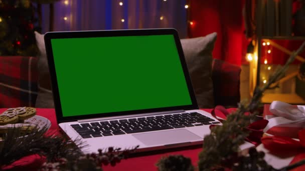 Otwórz laptop z zielonym ekranem chrom klucz na stole wśród pudełek świątecznych i dekoracje z girlandy światła na tle. Miejsce na reklamę, promocje noworoczne. Zamknij drzwi. Zwolniony ruch. — Wideo stockowe