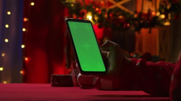 Mujer utiliza un teléfono inteligente para ver el contenido, comunicarse en las redes sociales. Decoraciones interiores de Navidad en colores rojos. Las manos femeninas tocan el teléfono con una tecla de croma de pantalla verde. Movimiento lento — Vídeos de Stock