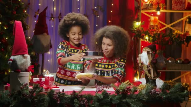 African American mom and daughter in bright holiday sweaters having fun and making dough for the holiday homemade cookies. Happy family portrait, New Years celebration concept. — Stock Video