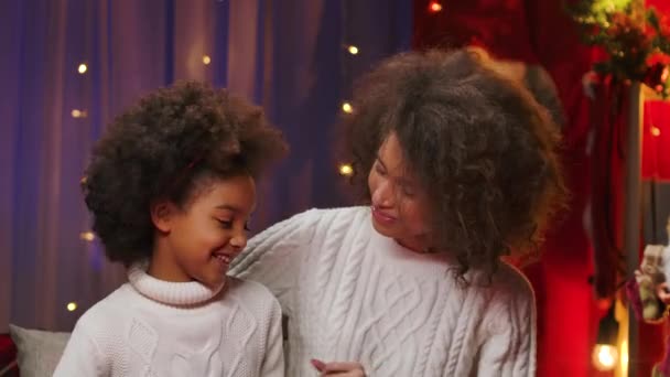 Афроамериканская мама и маленькая дочь в белых свитерах с радостью поют песни и веселятся. Счастливый семейный портрет, концепция празднования Нового года. Закрыть. — стоковое видео