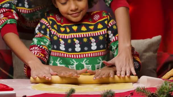 Afro-Amerikaanse moeder en dochtertje in heldere vakantie truien rollen samen het deeg uit voor zelfgemaakte koekjes. Gelukkig familieportret, Nieuwjaarsviering concept. Sluiten.. — Stockvideo