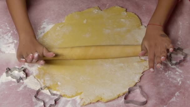 Küçük Afrikalı Amerikalı bir kızın elleri geleneksel Noel kurabiyeleri için hamuru yuvarlamak için merdane kullanıyor. Una bulanmış mutfak masası. Yavaş çekim. — Stok video