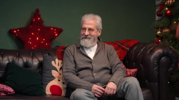Menino bonito surpreendeu seu avô com um presente incrível para a véspera de Natal. Um avô idoso abraça seu neto em uma sala decorada perto de uma árvore de Natal brilhante. Movimento lento. — Vídeo de Stock