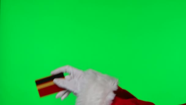 Papai Noel mãos em terno vermelho e luvas brancas estão segurando um cartão bancário. Isolado em tela verde no estúdio. Chave Chroma. Fecha. Movimento lento. — Vídeo de Stock